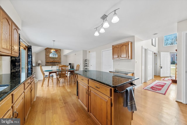 kitchen featuring lofted ceiling, light wood-style floors, and dark stone counters