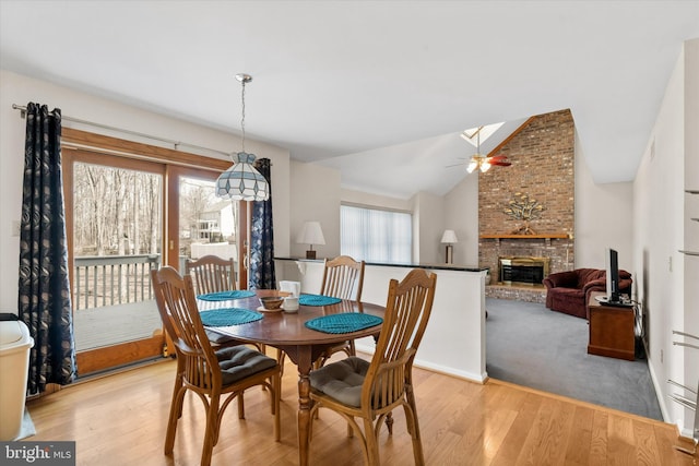 dining room featuring lofted ceiling with skylight, plenty of natural light, and light wood finished floors