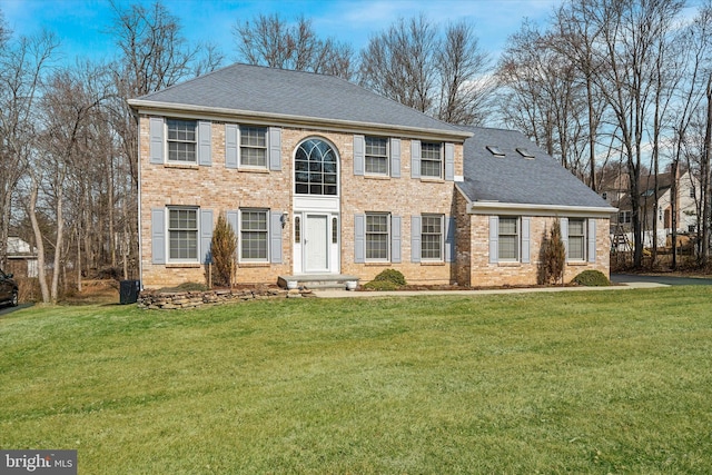 view of front of property featuring brick siding, a shingled roof, and a front lawn