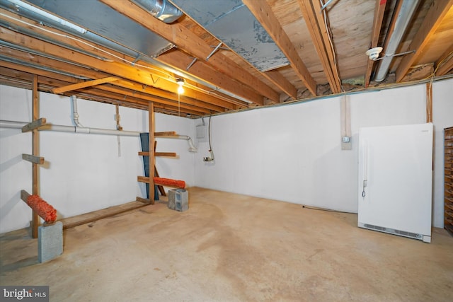 unfinished basement featuring freestanding refrigerator