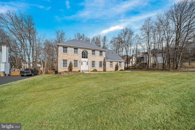 view of front of house with brick siding, aphalt driveway, and a front yard