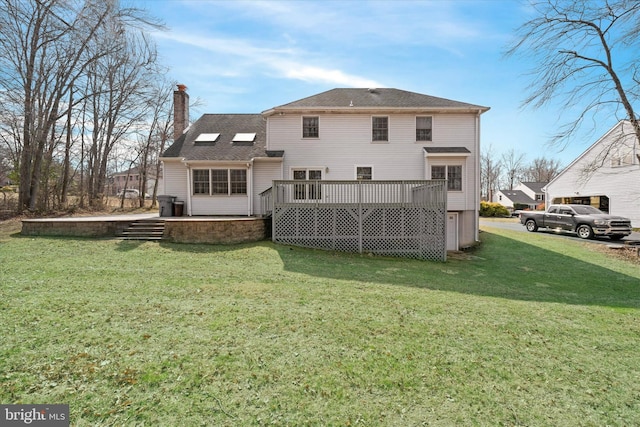 rear view of property featuring a chimney, a wooden deck, and a yard