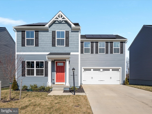 view of front of property with a front yard, driveway, a garage, and roof mounted solar panels