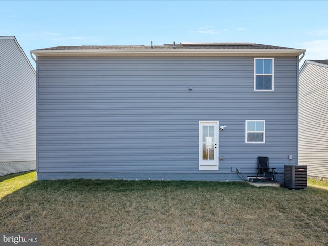 back of house featuring central air condition unit and a lawn