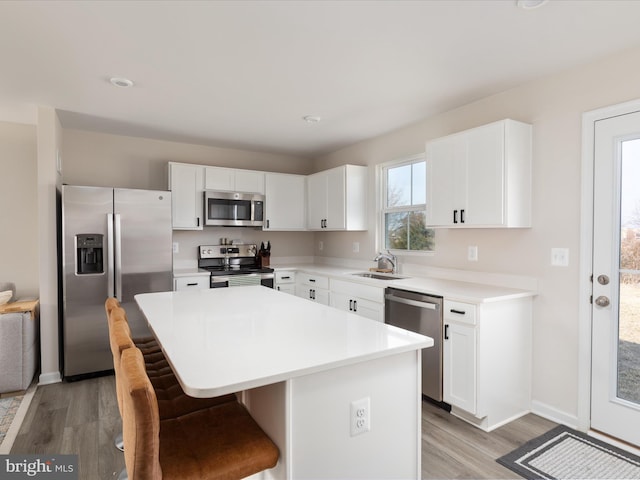 kitchen featuring a breakfast bar area, light wood finished floors, appliances with stainless steel finishes, and a center island