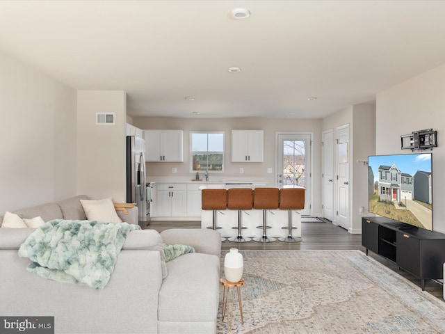 living room featuring wood finished floors, visible vents, and baseboards