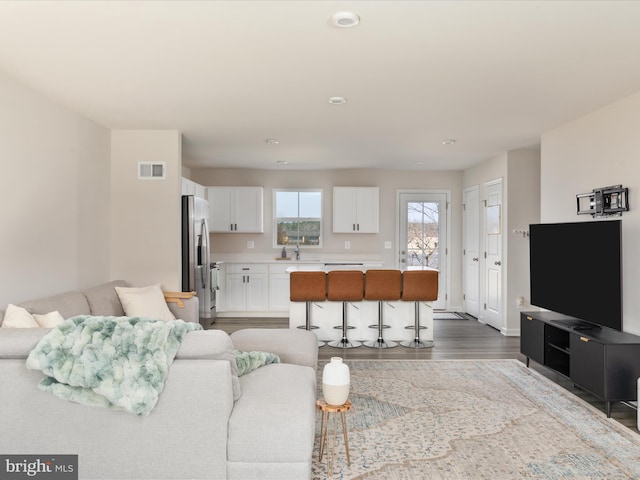 living area with wood finished floors, visible vents, and baseboards