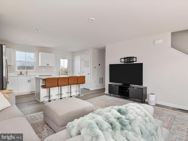 living room featuring visible vents, baseboards, and light wood-style floors