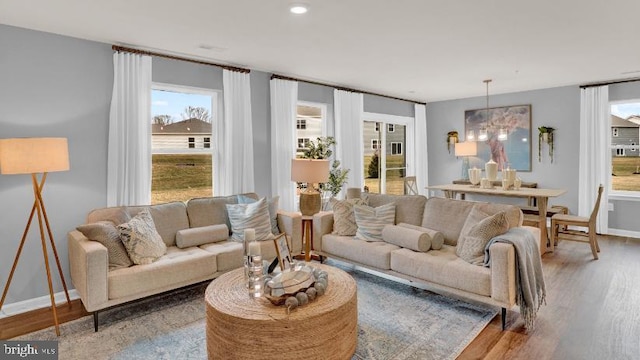 living room with a chandelier, baseboards, and wood finished floors