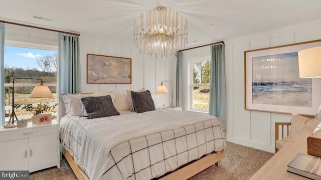 bedroom with multiple windows, a chandelier, carpet flooring, and a decorative wall