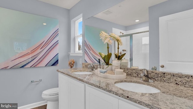 full bathroom featuring double vanity, a stall shower, toilet, and a sink