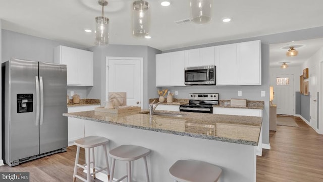 kitchen featuring light wood-type flooring, visible vents, a sink, stainless steel appliances, and white cabinets