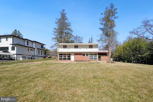 back of house featuring brick siding and a lawn