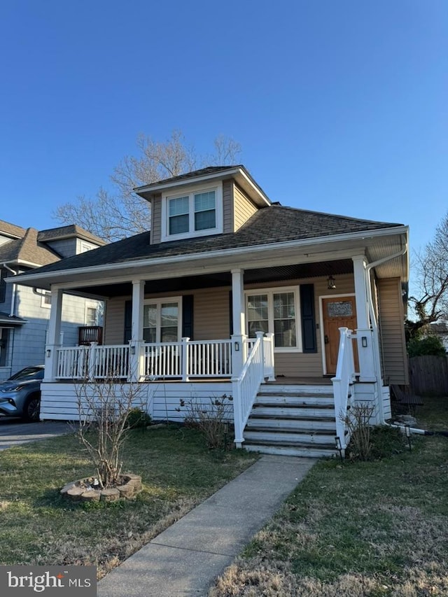 bungalow-style house with a porch, a front lawn, and a shingled roof