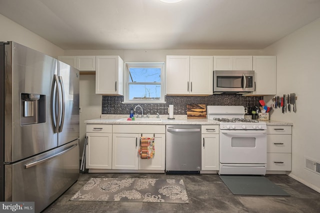 kitchen featuring a sink, stainless steel appliances, light countertops, white cabinetry, and backsplash