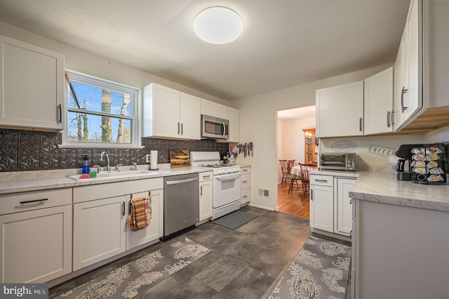 kitchen with visible vents, a sink, stainless steel appliances, white cabinetry, and tasteful backsplash