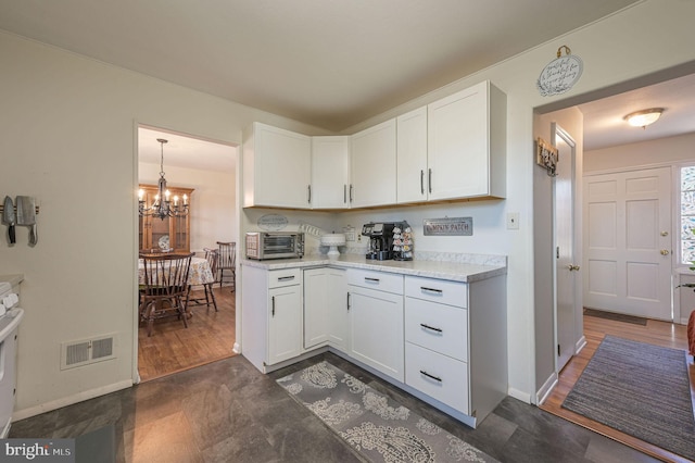 kitchen featuring baseboards, visible vents, light countertops, white cabinetry, and a notable chandelier