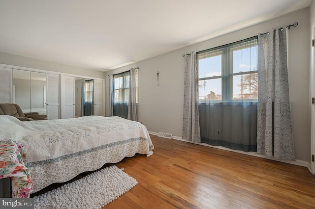 bedroom featuring wood finished floors, visible vents, two closets, and baseboards