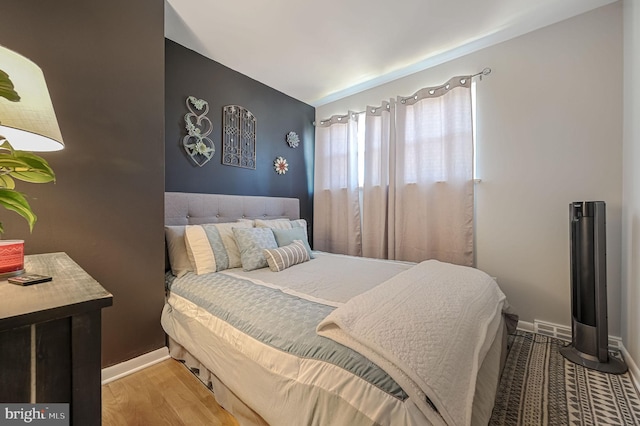 bedroom with visible vents, baseboards, vaulted ceiling, and light wood finished floors