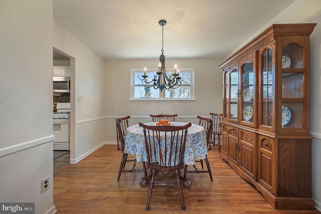 dining room with wood finished floors, baseboards, and a chandelier