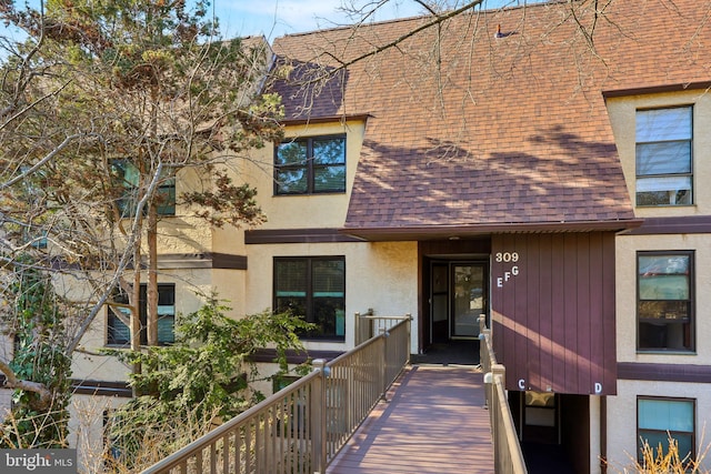 exterior space with stucco siding and roof with shingles