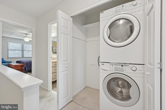 laundry area featuring light colored carpet, ceiling fan, laundry area, and stacked washing maching and dryer