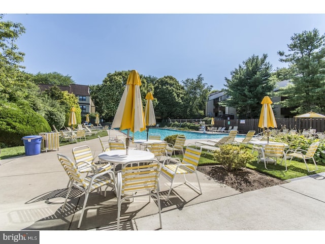 view of patio with a community pool and fence