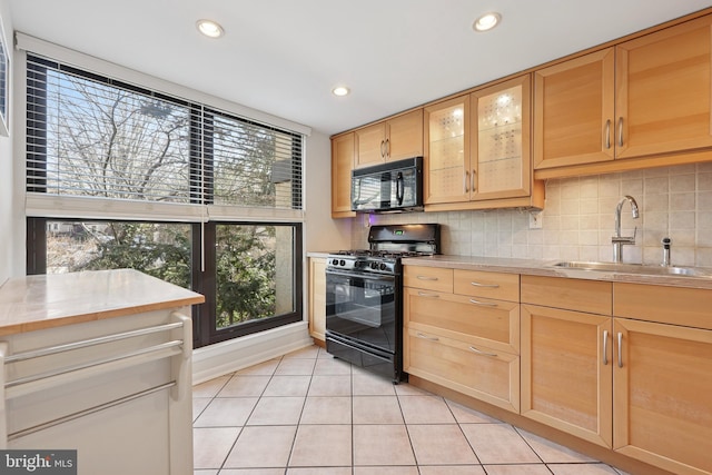 kitchen with black appliances, light brown cabinets, a sink, backsplash, and light countertops