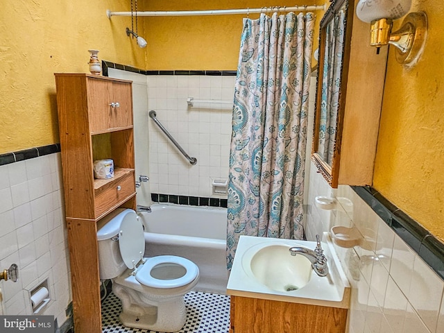 full bath with toilet, wainscoting, a textured wall, tile walls, and shower / bathtub combination with curtain