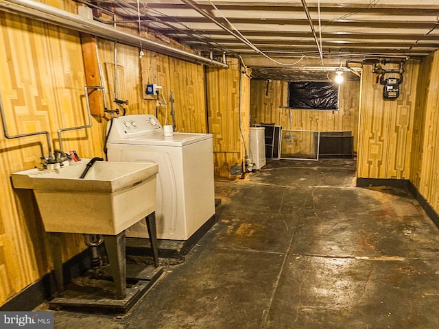 unfinished below grade area with wooden walls, washer / clothes dryer, and a sink