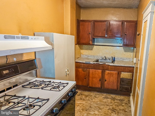 kitchen with under cabinet range hood, white range with gas cooktop, light countertops, and a sink