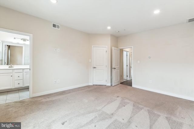 unfurnished bedroom with visible vents, light carpet, ensuite bathroom, a sink, and recessed lighting