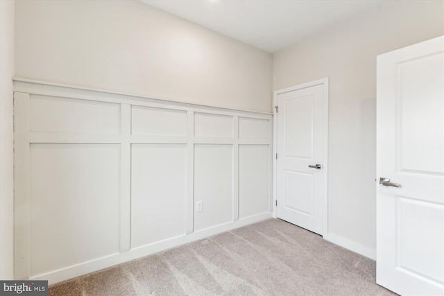 unfurnished bedroom featuring a closet, light carpet, and a decorative wall