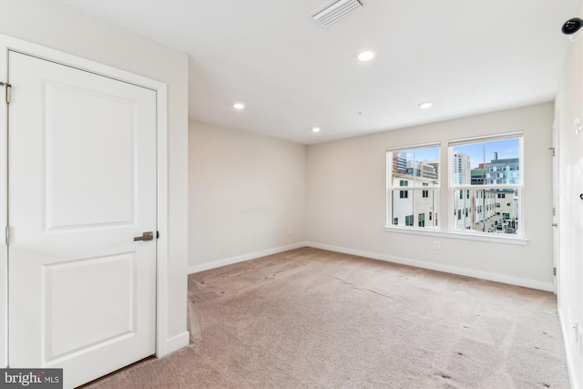 carpeted spare room with recessed lighting, visible vents, baseboards, and a view of city