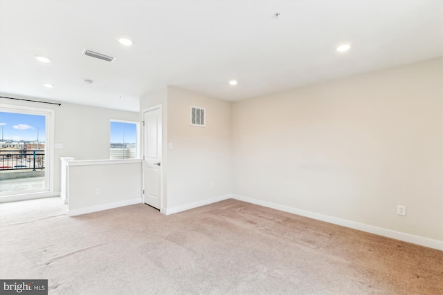 empty room featuring light carpet, visible vents, recessed lighting, and baseboards