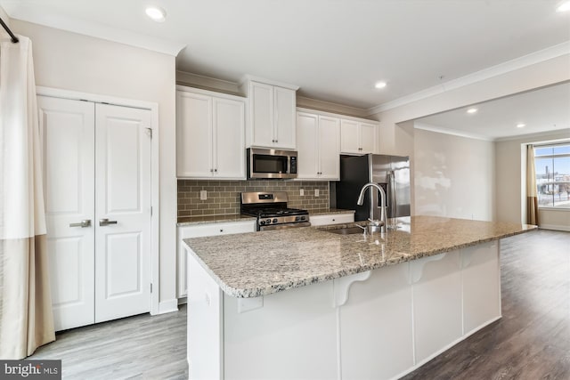 kitchen with decorative backsplash, crown molding, light wood finished floors, and stainless steel appliances