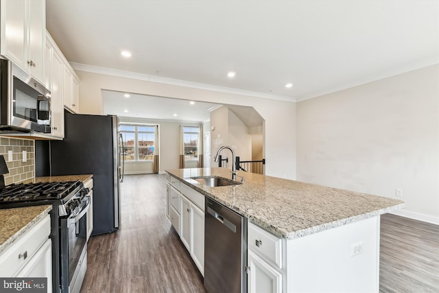 kitchen featuring dark wood finished floors, an island with sink, a sink, appliances with stainless steel finishes, and tasteful backsplash