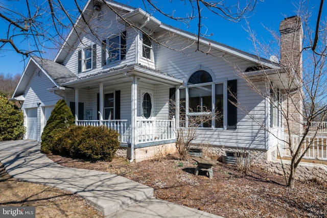 view of front of property with a porch, a chimney, a garage, and concrete driveway