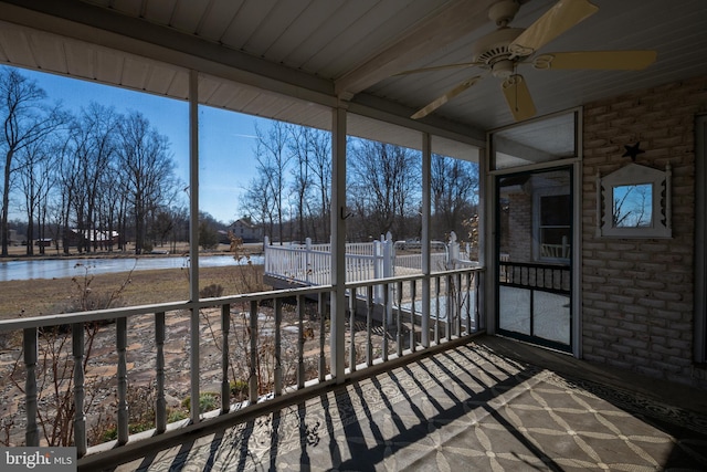 unfurnished sunroom with a ceiling fan and a water view