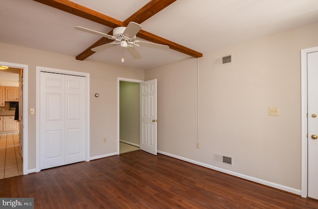 unfurnished bedroom with visible vents, baseboards, beamed ceiling, and wood finished floors