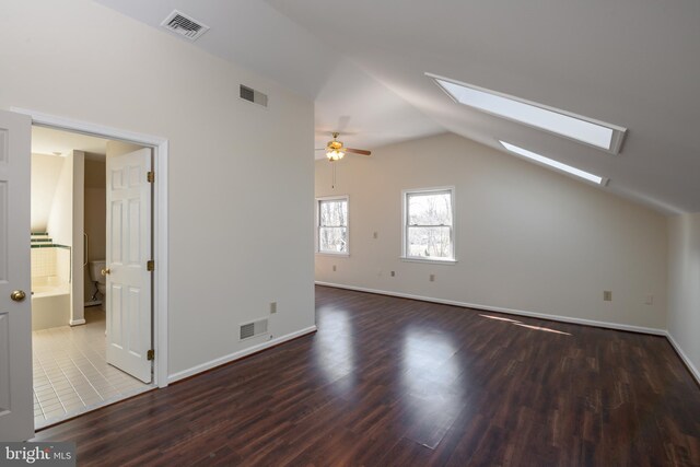 additional living space featuring visible vents, vaulted ceiling with skylight, and wood finished floors