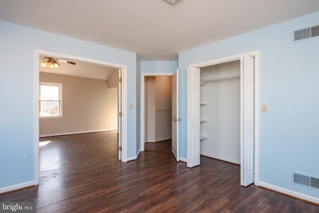 unfurnished bedroom with dark wood-style floors, visible vents, and baseboards