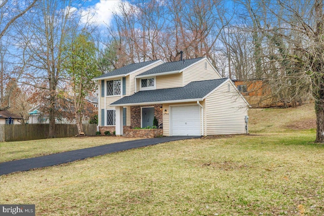 traditional-style house featuring brick siding, a front lawn, fence, aphalt driveway, and roof with shingles