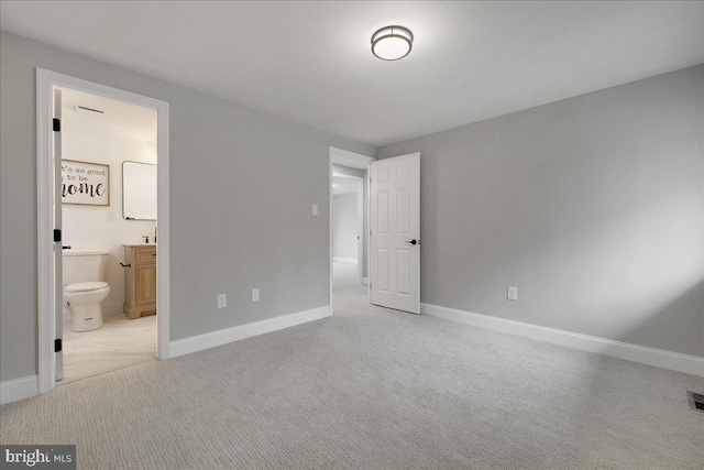 unfurnished bedroom featuring ensuite bath, visible vents, baseboards, and carpet floors