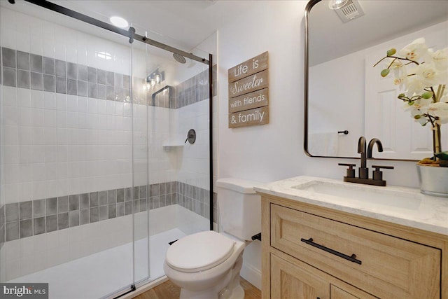 bathroom with visible vents, a shower stall, toilet, and vanity