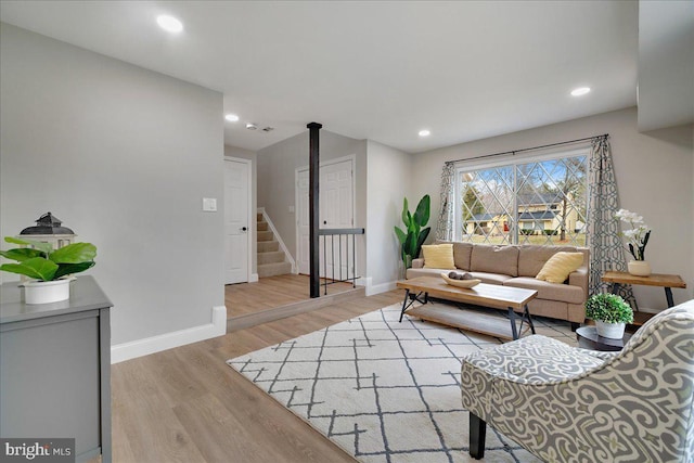 living area featuring stairs, recessed lighting, baseboards, and light wood-type flooring