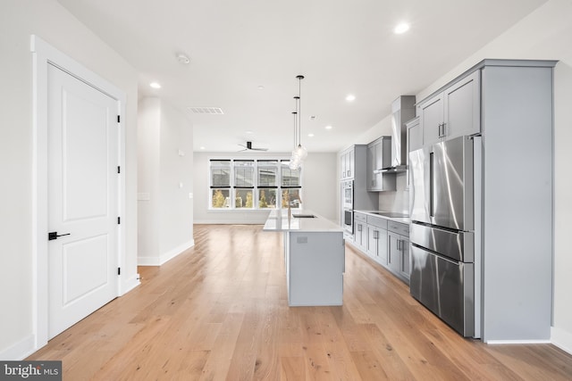 kitchen featuring freestanding refrigerator, ceiling fan, gray cabinetry, light countertops, and light wood-type flooring