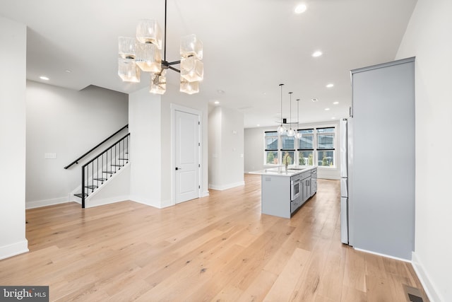 kitchen with light wood finished floors, recessed lighting, a sink, a notable chandelier, and open floor plan