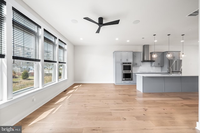 kitchen featuring visible vents, wall chimney range hood, ceiling fan, gray cabinets, and appliances with stainless steel finishes