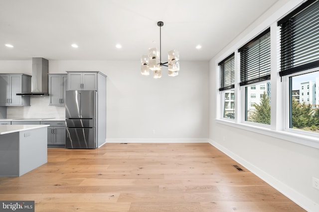 kitchen featuring light countertops, wall chimney exhaust hood, high quality fridge, and gray cabinets